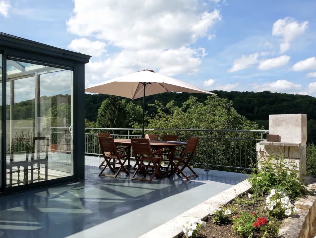 Terrace with dining table and umbrella overlooking the valley