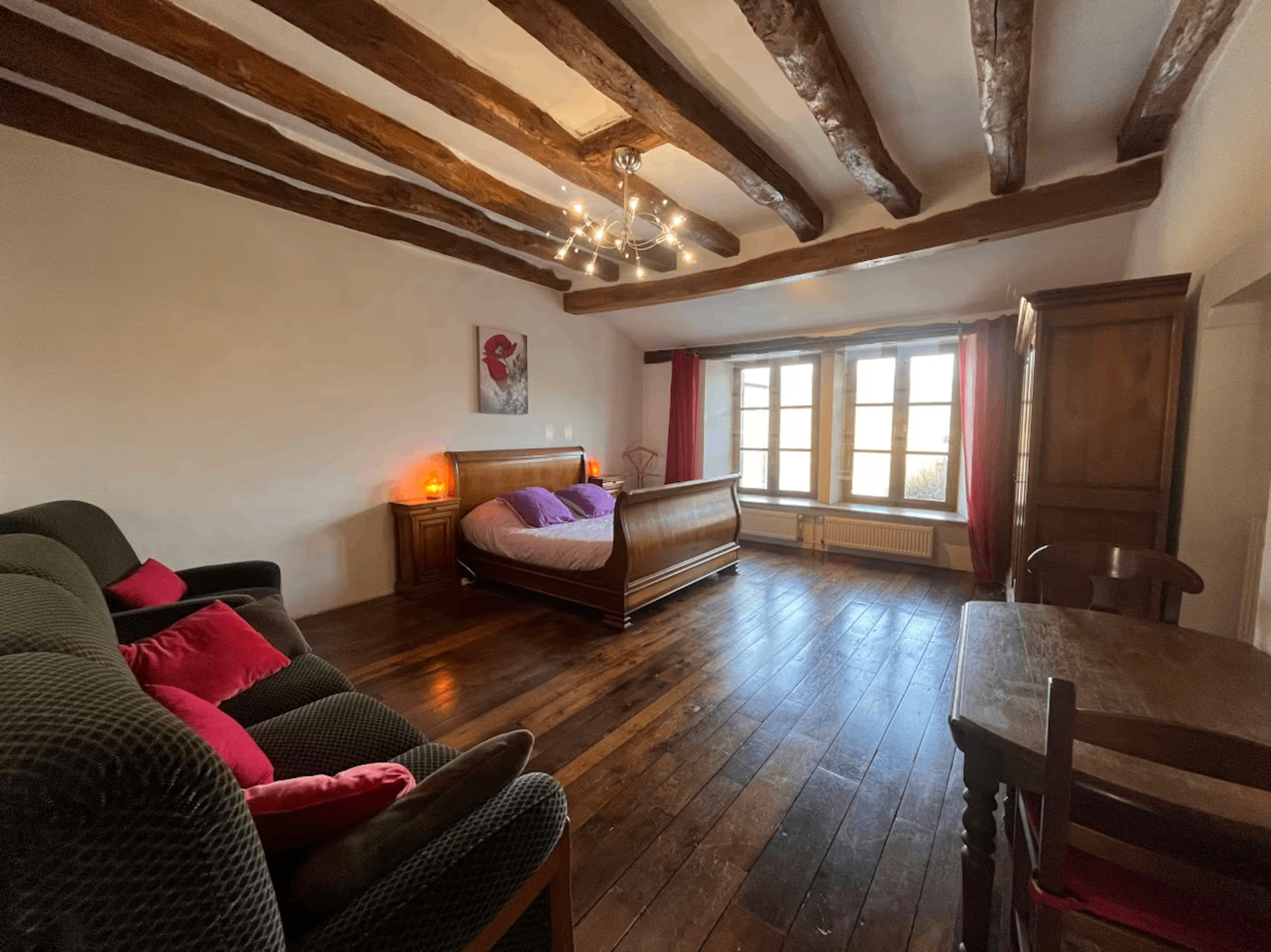 Large bedroom with beamed ceiling, sleigh bed, and wood floors