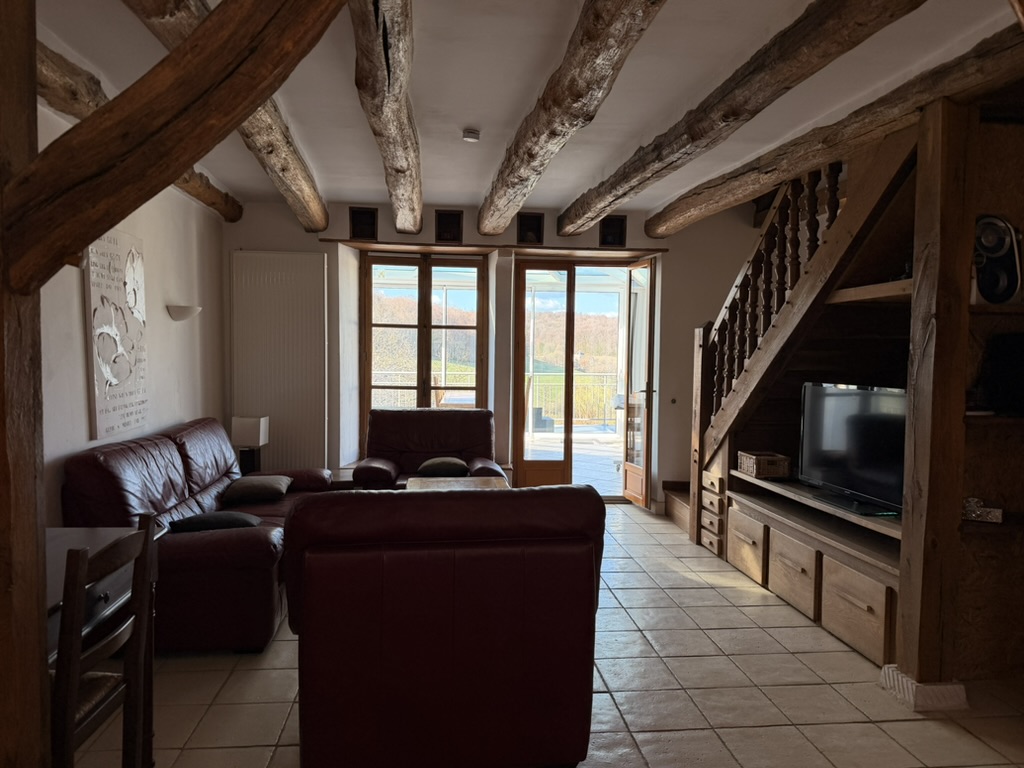 Living room with beams, staircase, and doors opening to the terrace