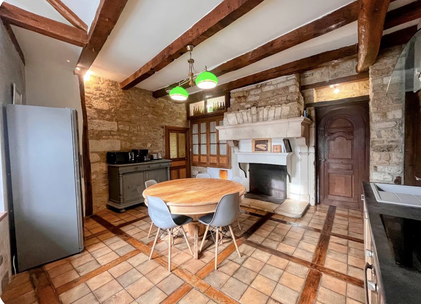 Country kitchen with stone walls, beams, and a large fireplace
