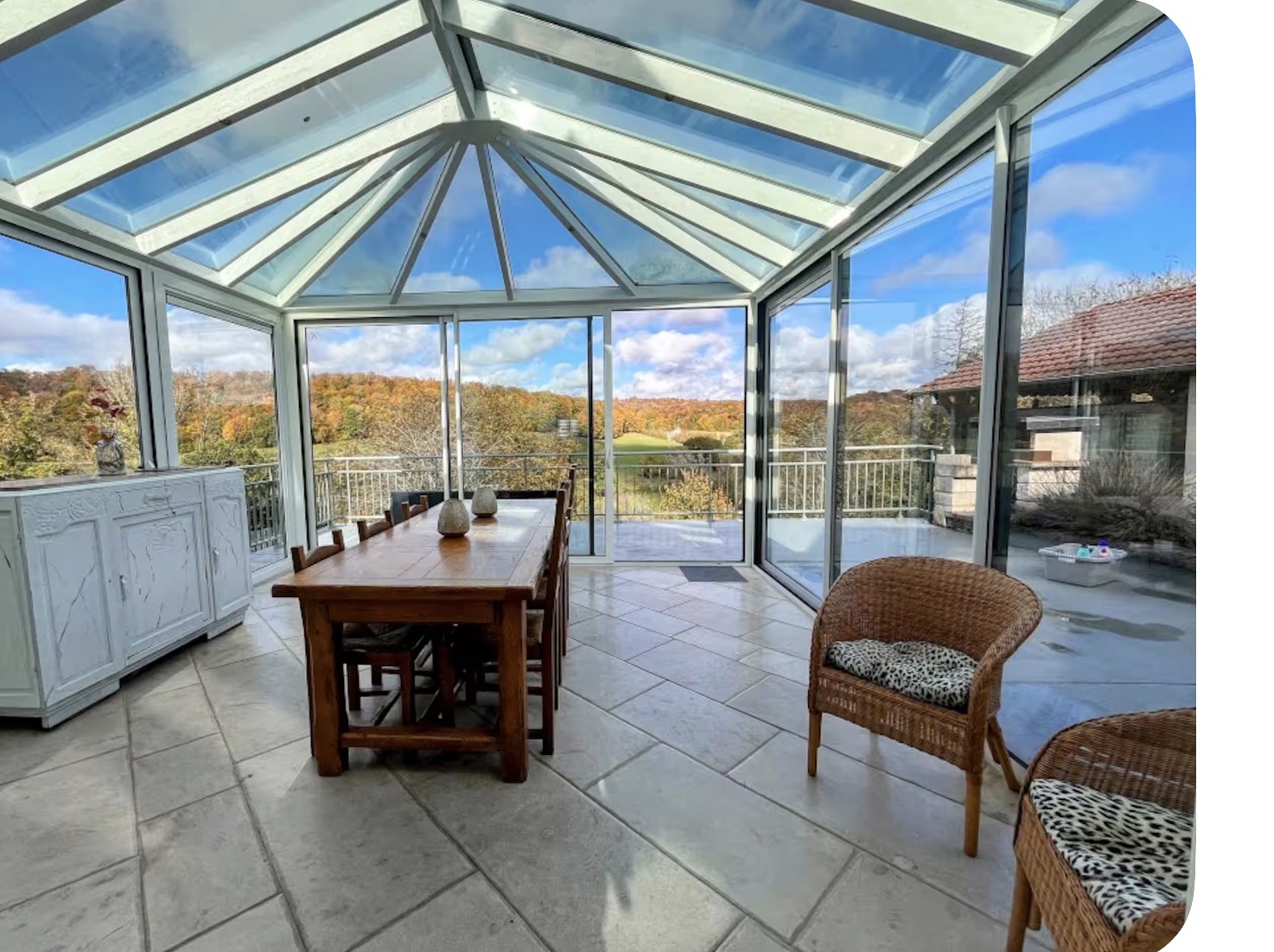 Glass veranda with long farmhouse table and countryside views