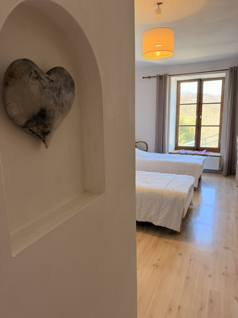 Stone heart in an arched alcove beside a light-filled twin bedroom