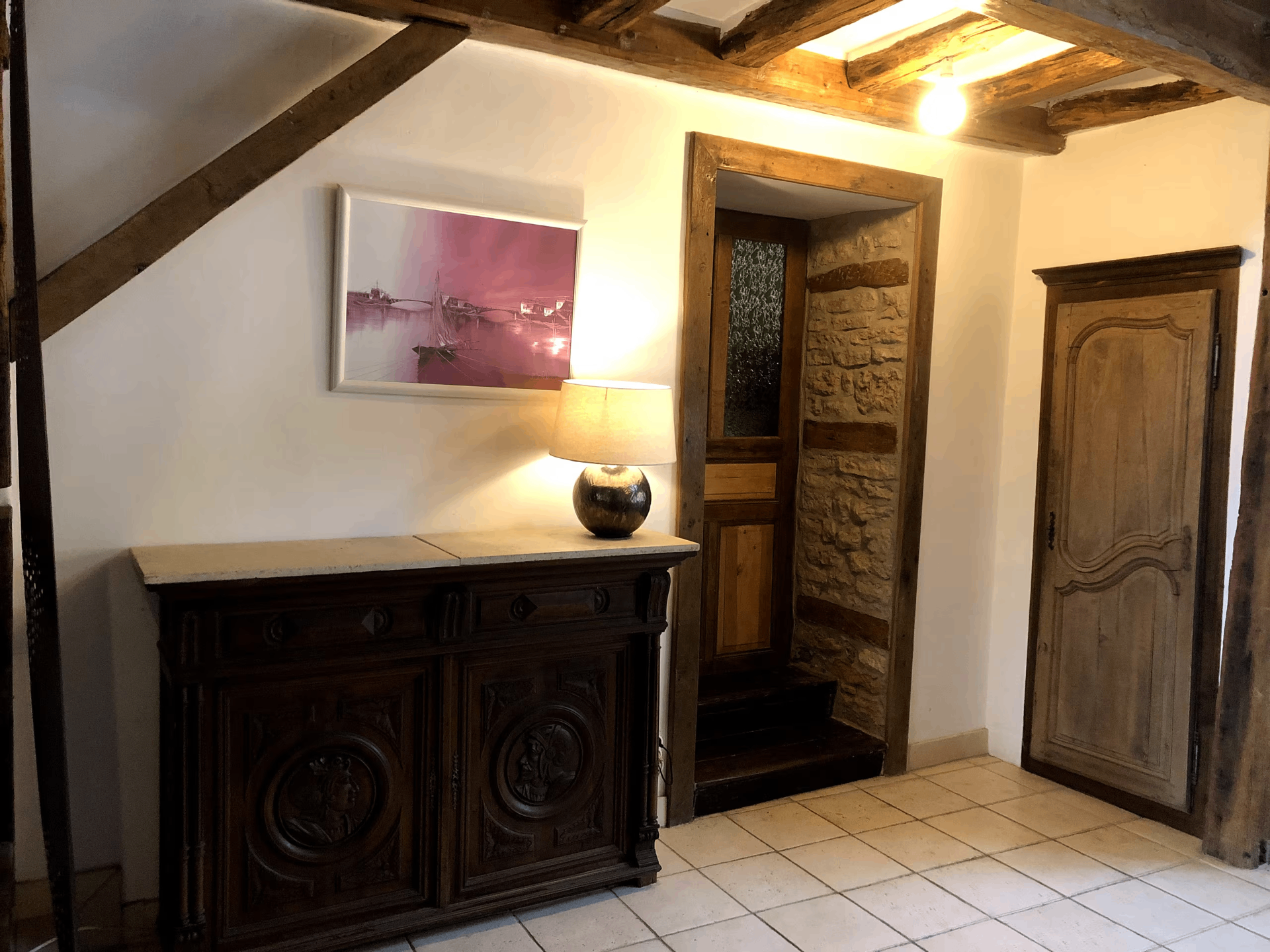 Entry hall with antique sideboard, lamp, and stone doorway