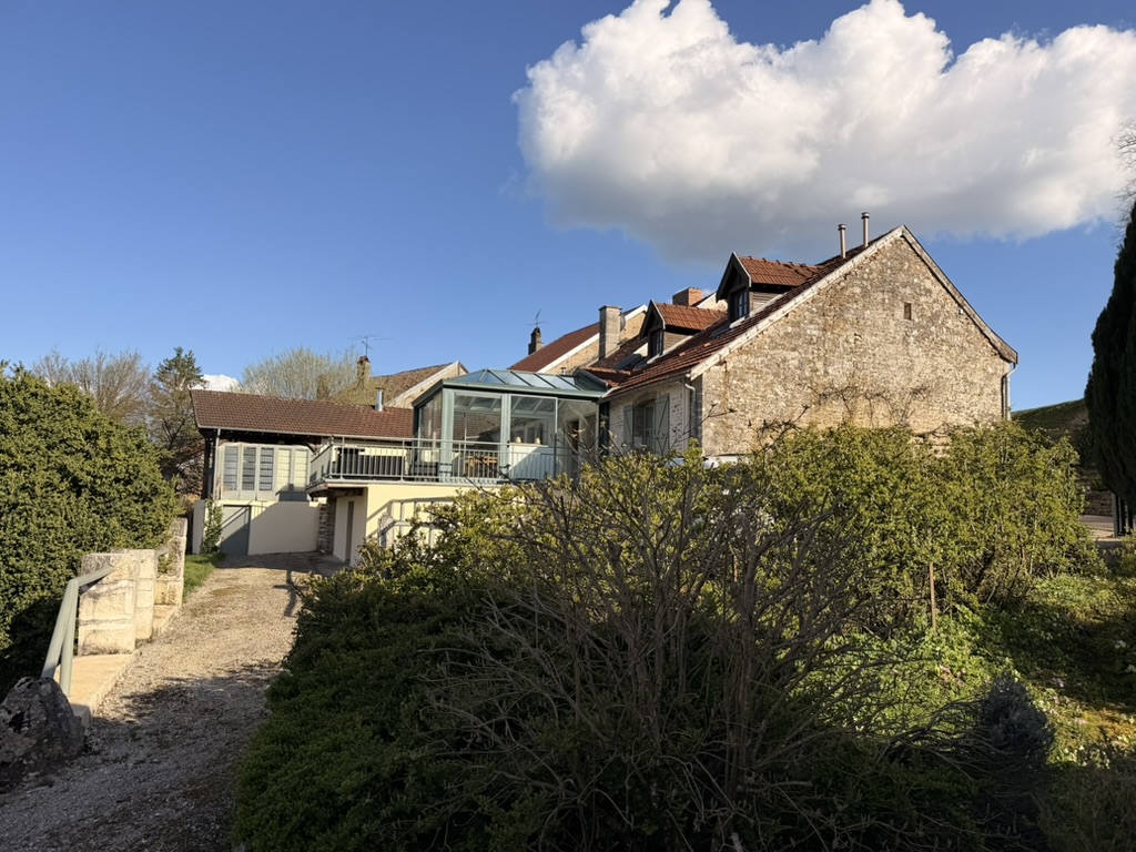 The stone house with its glass veranda under a blue sky